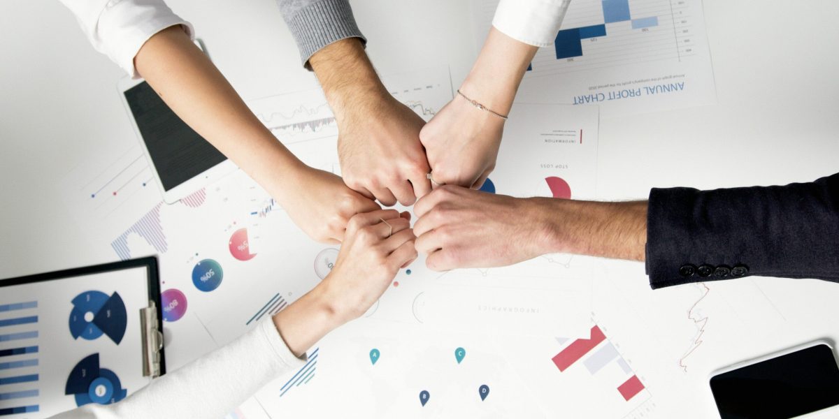 How-Smart-IT-Boosts-Employee-Morale-and-Keeps-Your-Best-People-scaled.jpg Smart IT Free Colleagues celebrate success with a fist bump over financial charts depicting teamwork and unity. Stock Photo