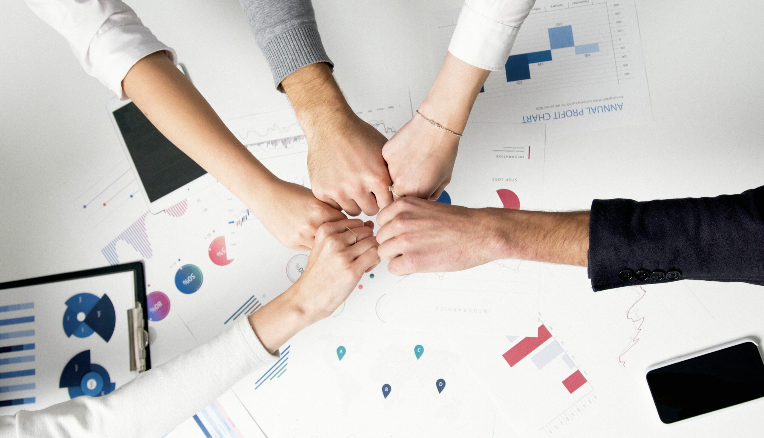 How Smart IT Boosts Employee Morale and Keeps Your Best People 1 Smart IT Free Colleagues celebrate success with a fist bump over financial charts depicting teamwork and unity. Stock Photo