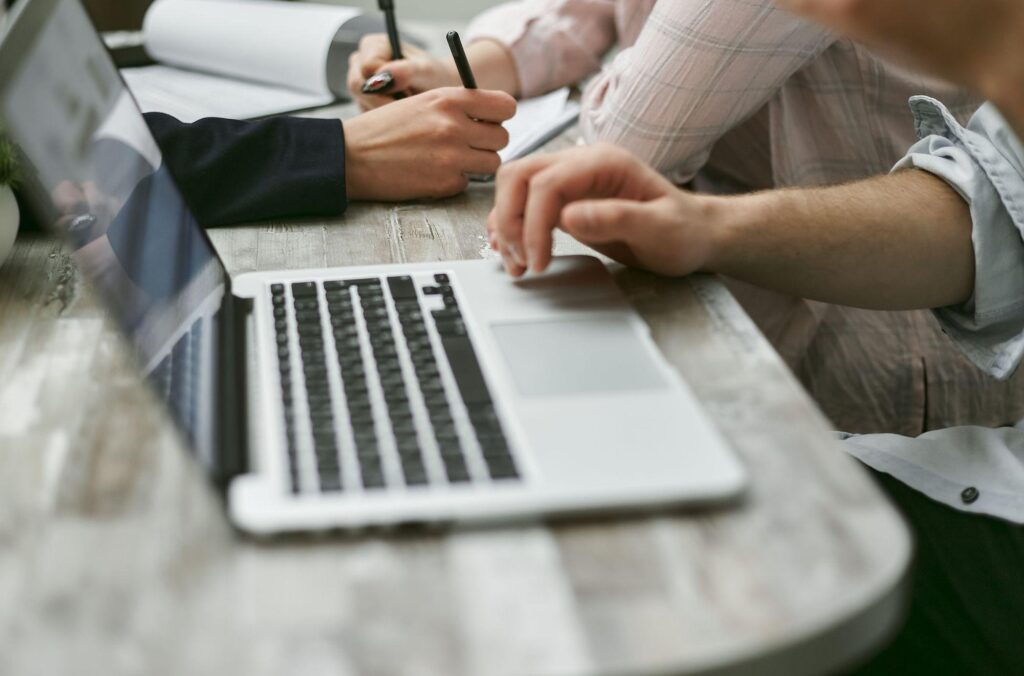 Administrator Access: 7 Simple Steps to Take It Back 2 Coworkers working on a laptop and taking notes at a shared desk